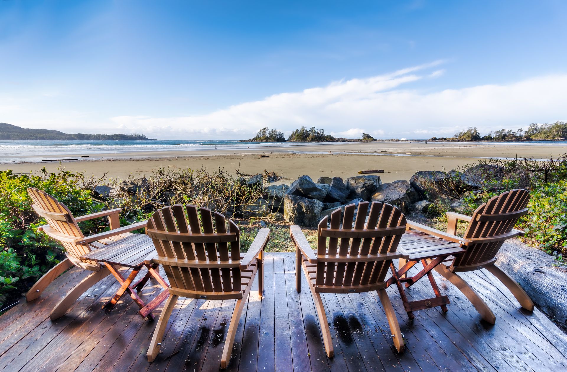 Relaxing view of Tofino beach with Adirondack chairs on a sunny day.