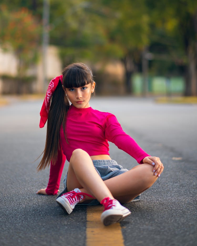 Teenager Girl In Hot Pink Shirt Sitting On Street