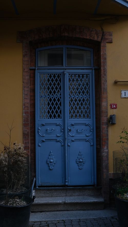 Free A classic vintage blue door with ornate wrought iron detailing in a brick archway. Stock Photo