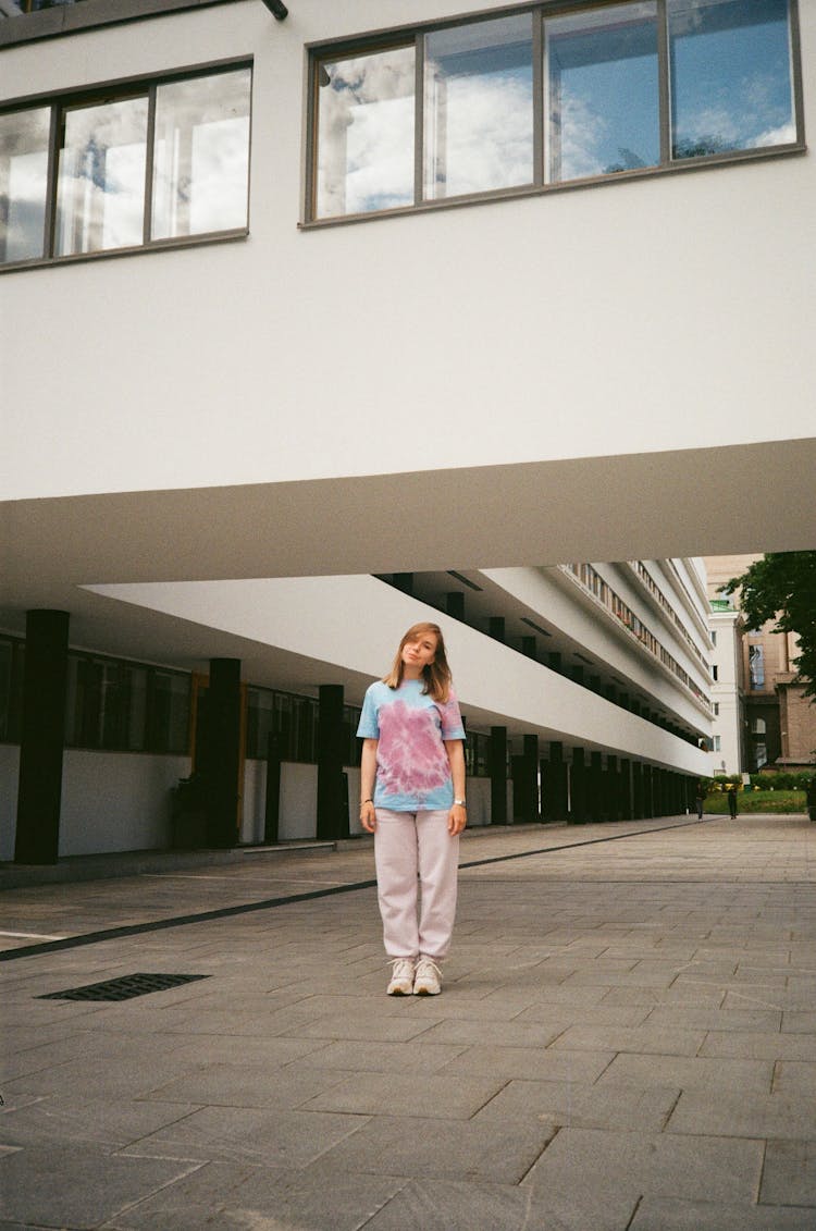 Woman Standing On The Pavement Below A Skywalk