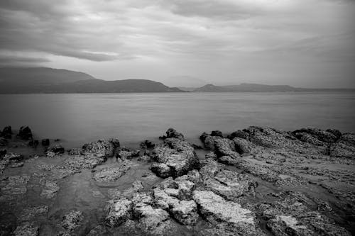 Black and White Photo of Sea and Rocky Coastline