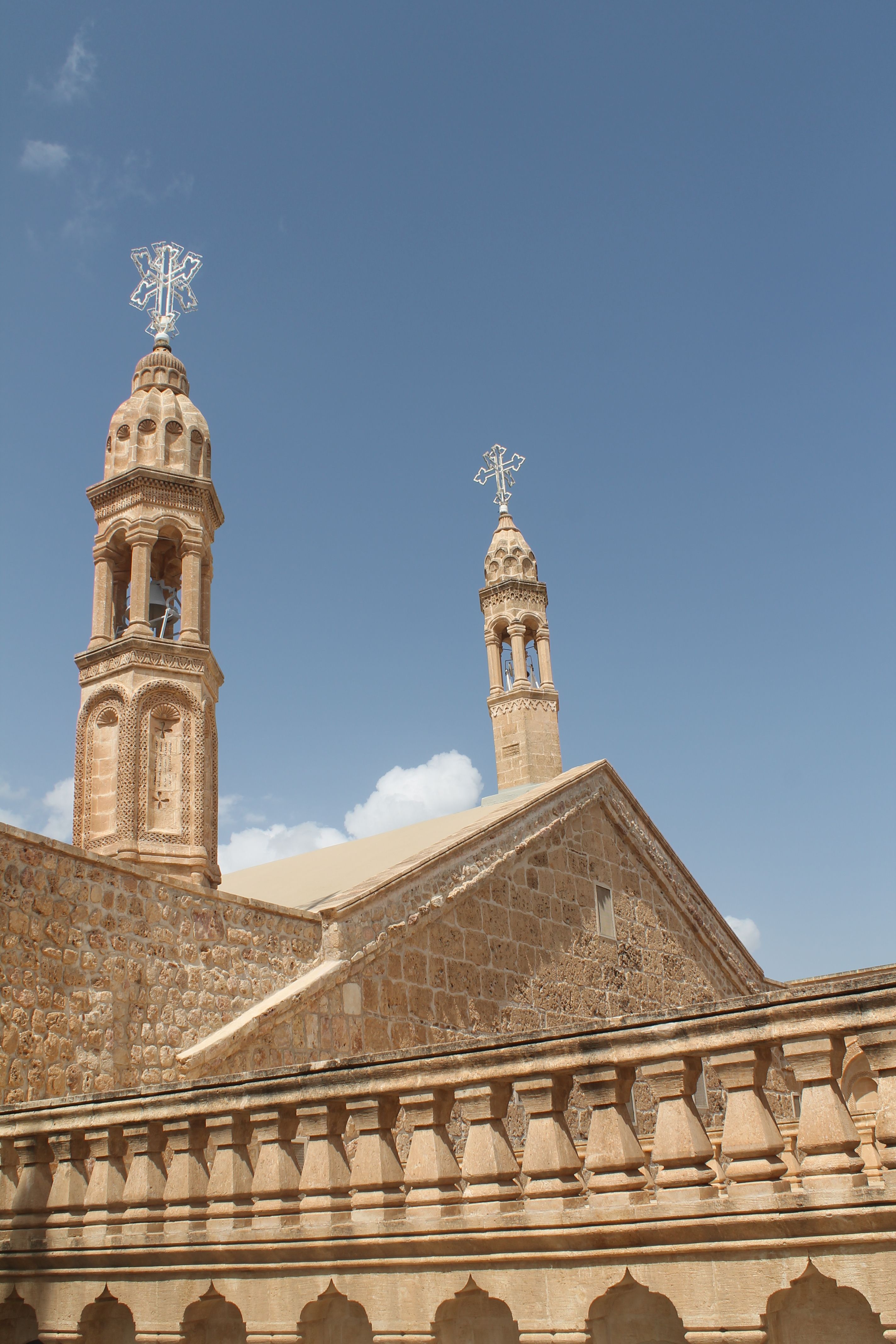 Captivating view of ancient monastery towers under a clear blue sky in Mardin, Türkiye.