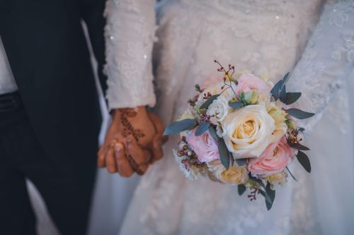 Free Close-up of a bride and groom's hands with a beautiful bouquet, capturing the essence of a romantic Paris wedding. Stock Photo