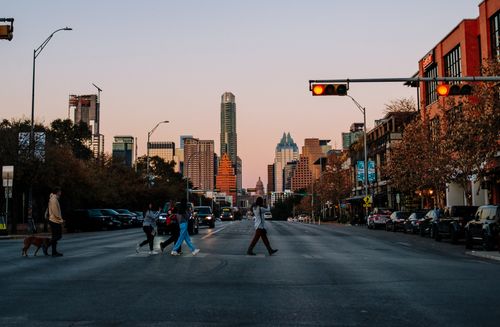 Free People crossing a city street in Austin, Texas at sunset with the skyline in the background. Stock Photo