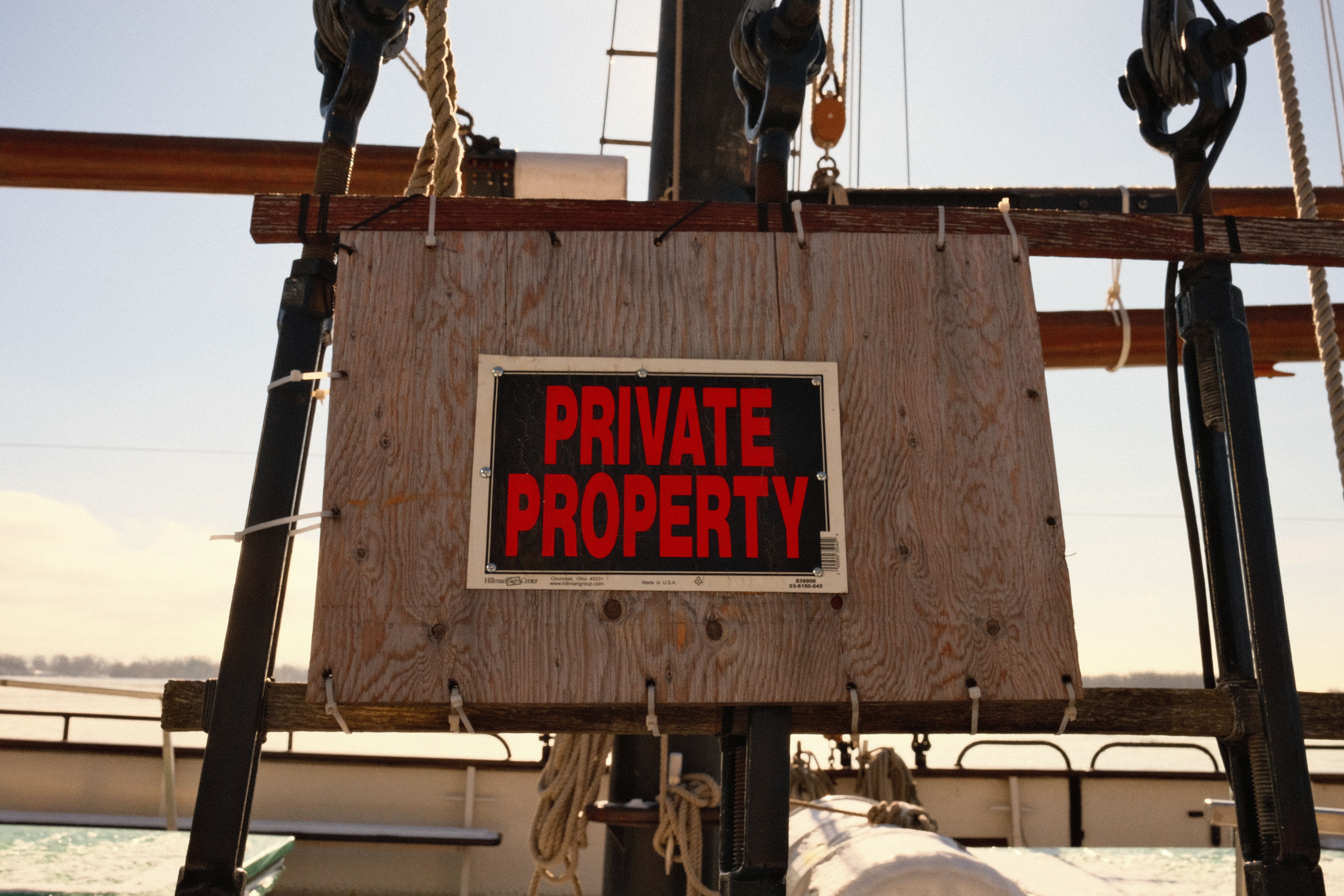Close-up of a private property sign mounted on a sailboat's rigging outdoors.
