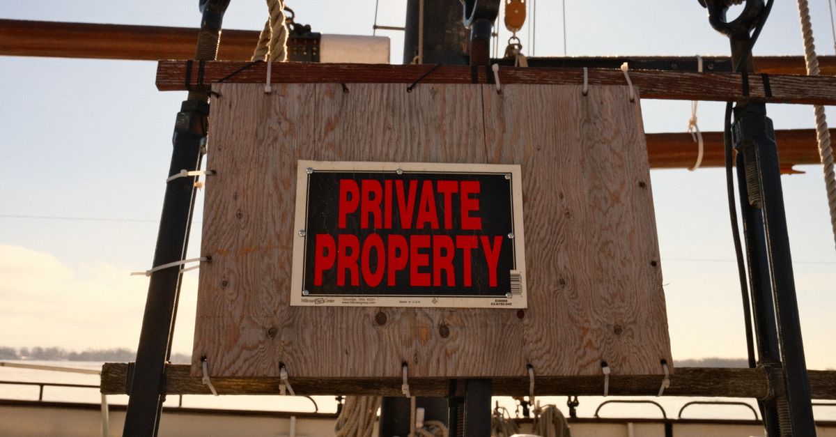 Close-up of a private property sign mounted on a sailboat's rigging outdoors.