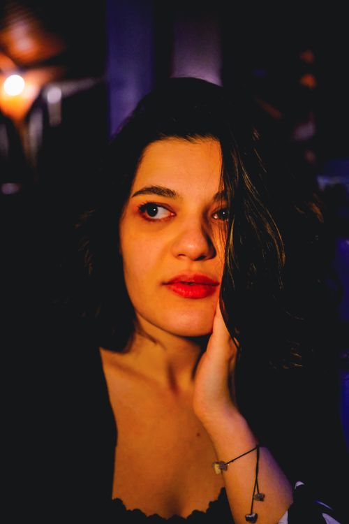 Free A thoughtful young woman with brunette hair in a dimly lit indoor setting, exuding a serene and introspective mood. Stock Photo