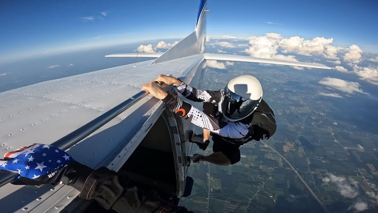 A Skydiver Holding Onto The Side Of An Aircraft