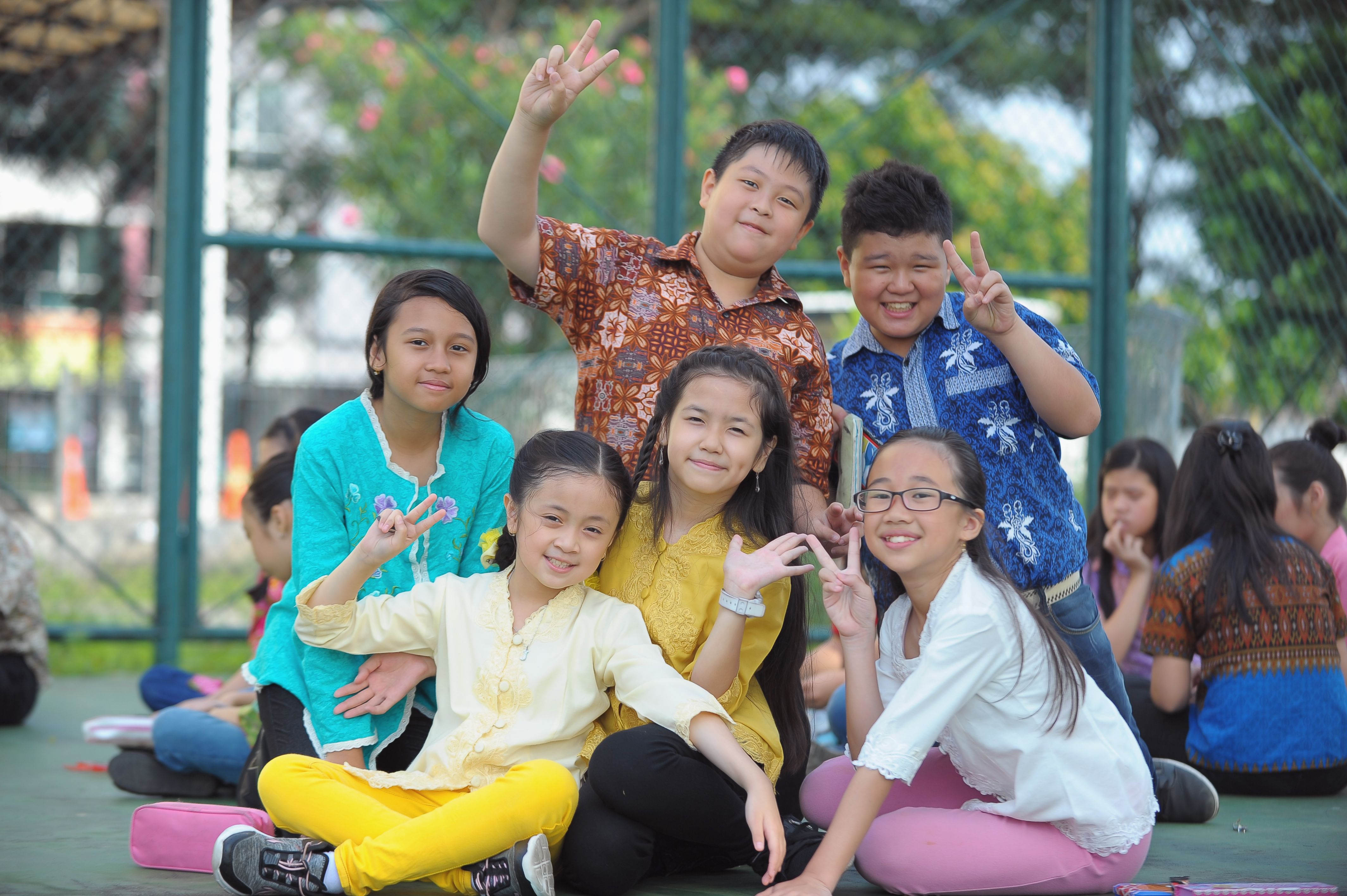Group of joyful Asian children posing outdoors at a playground.