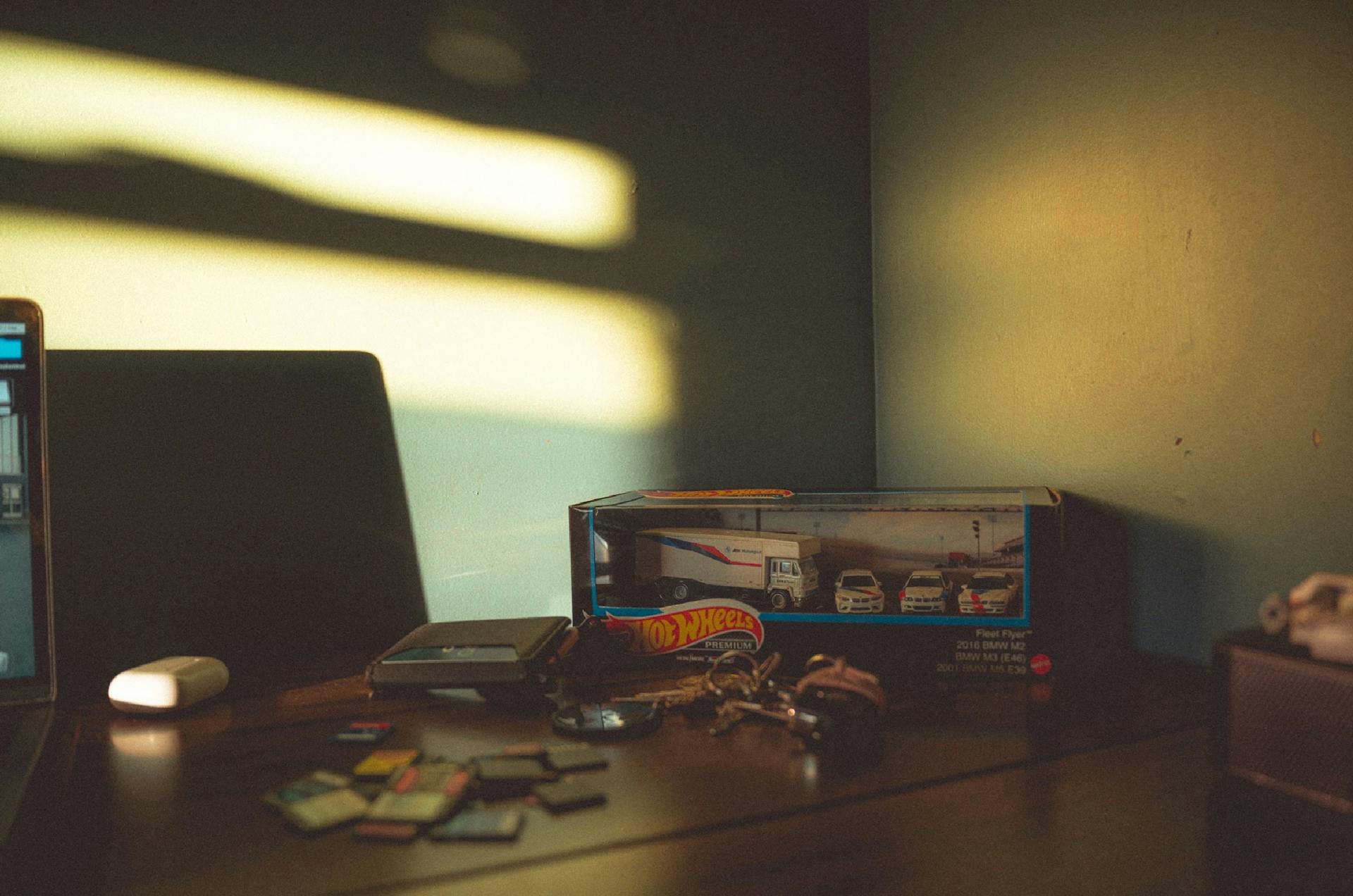 A desk with Hot Wheels cars and scattered gadgets in warm sunlight. Perfect for nostalgia themes.