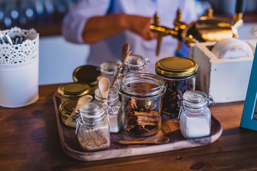 Warm kitchen scene with glass jars of spices on a wooden tray, perfect for culinary themes.