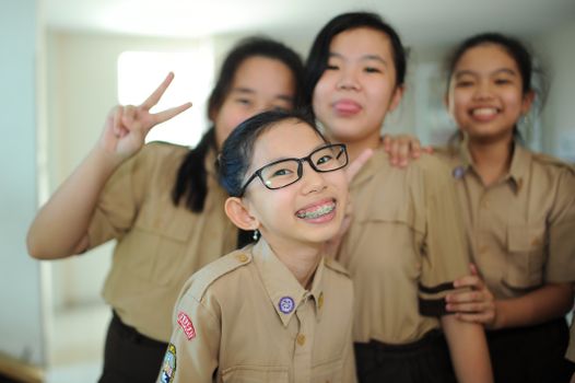 Smiling group of schoolgirls posing together indoors, exuding joy and energy.
