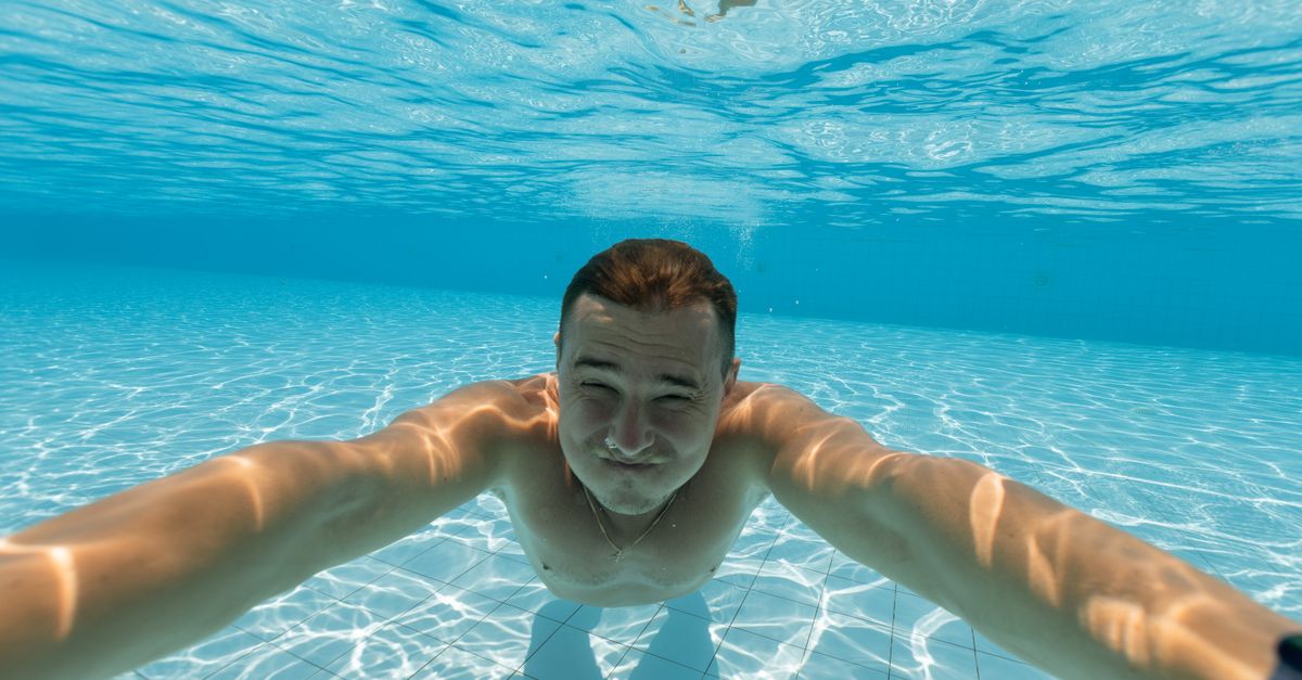 Man smiling underwater in a bright pool showing aquatic serenity.