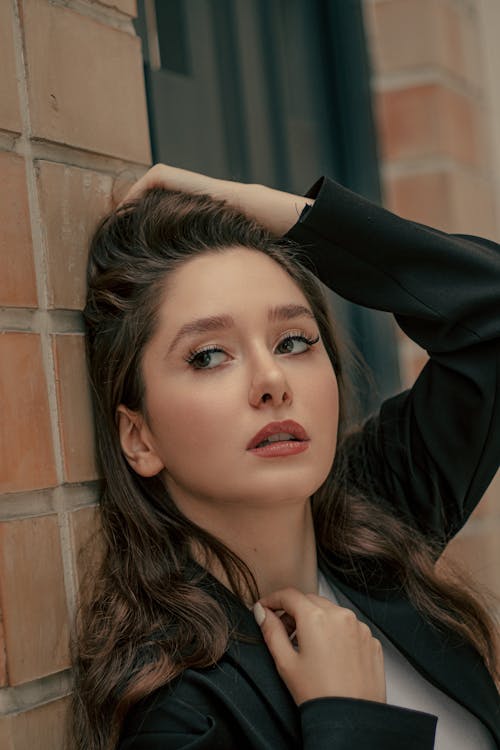 Close-Up Photo of Woman leaning on Brickwall