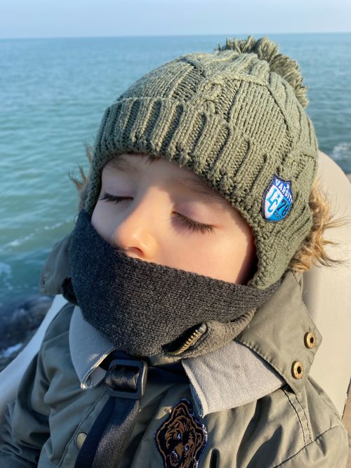 Free Young child sleeping by the sea in winter, wearing warm clothing and a wool cap. Stock Photo
