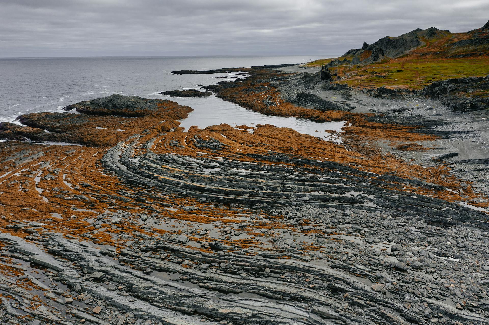 Explore the unique layered rocky coastline of Murmansk under an overcast sky.