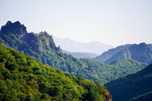 A stunning view of lush green mountains and forests under a clear sky., free online jigsaw puzzle on JigsawPuzzlesFreeOnline.org