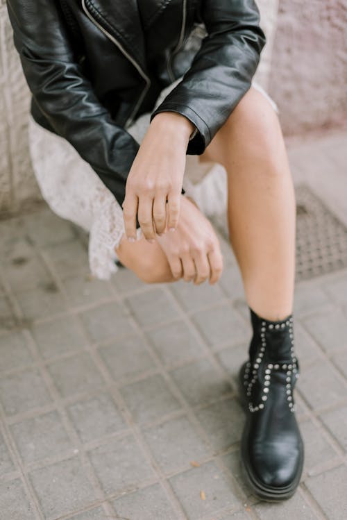 Foto profissional grátis de agachado, botas pretas, calçada