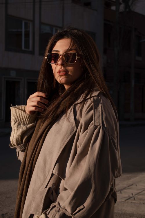 Free Fashionable woman wearing sunglasses and coat in moody urban environment. Stock Photo