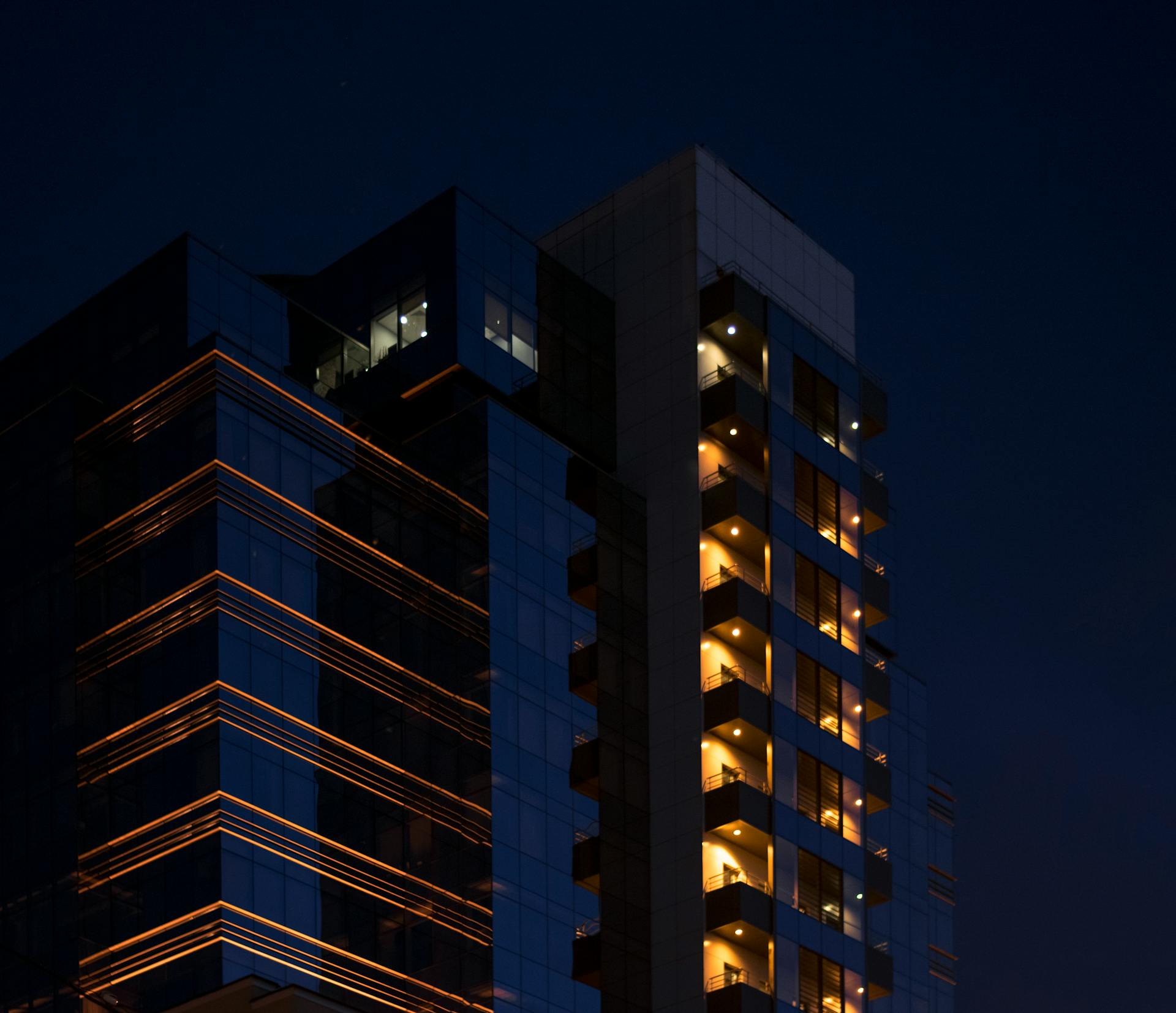 Contemporary building in Kyiv with illuminated balconies against a night sky.