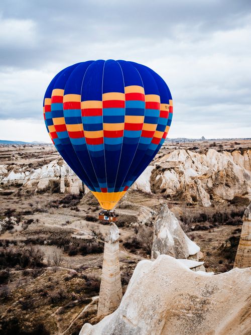 Free Vibrant hot air balloon flying over the unique rock formations of Cappadocia, Turkey. Stock Photo