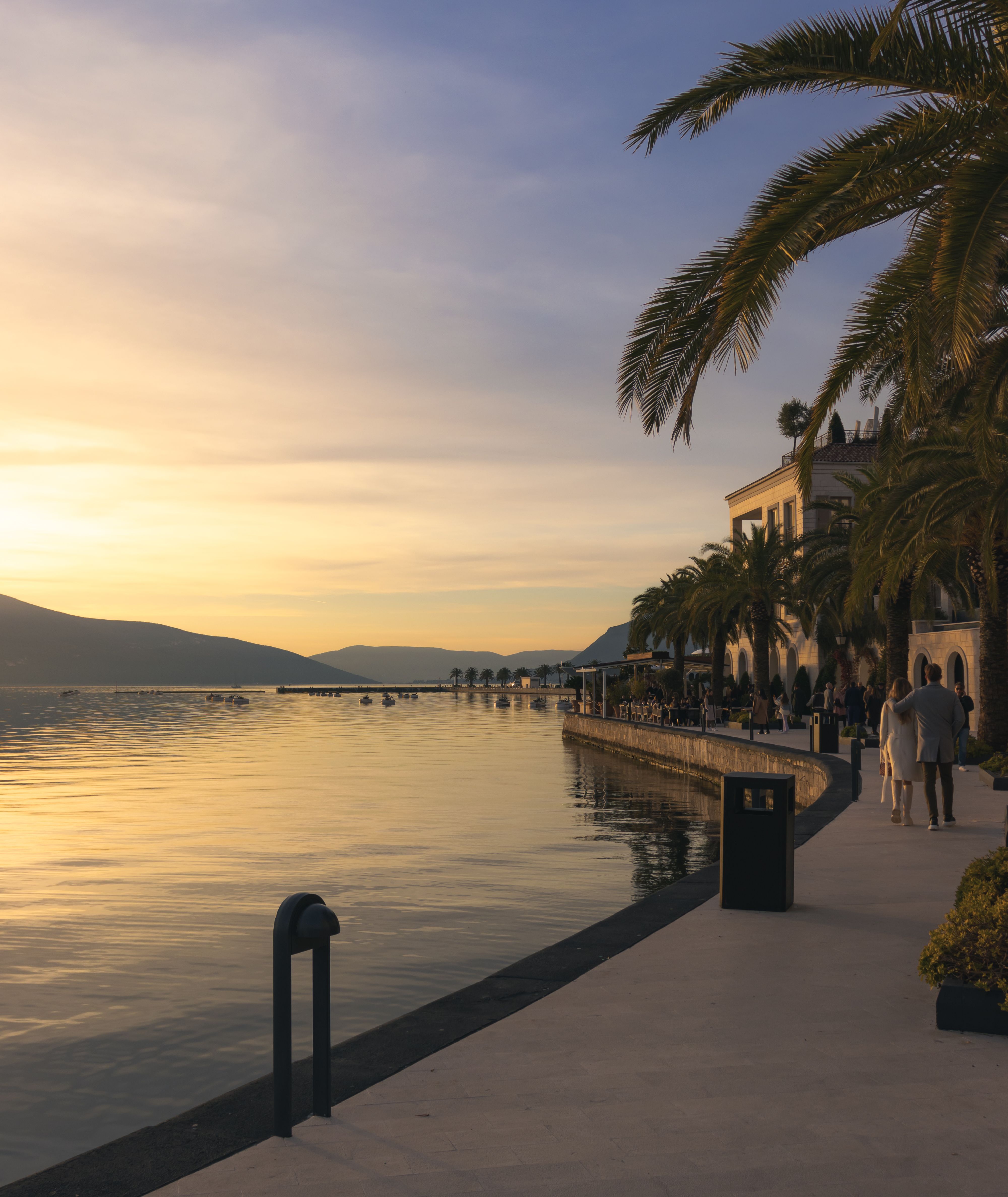 Relaxed free-time moment during a corporate retreat in Quang Ninh, attendees walking by the bay and enjoying coffee, balanced itinerary concept, soft golden hour light