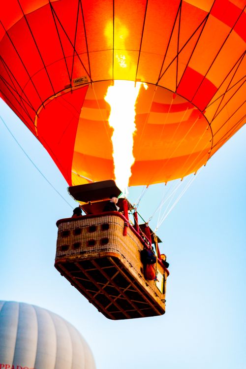 Free Colorful hot air balloon flying through the sky with fiery lift-off flame, showcasing adventure and travel. Stock Photo
