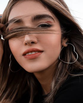 A vibrant close-up portrait showcasing a smiling woman with wind-swept hair and bold makeup