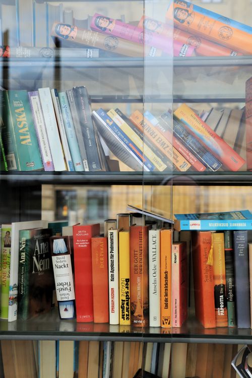 Free Vibrant books neatly arranged in a glass bookshelf at a Düsseldorf bookstore. Stock Photo