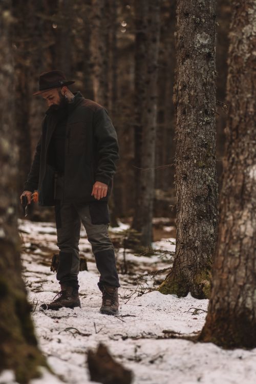 Free A man dressed as a lumberjack, holding an axe in a snowy winter forest. Stock Photo