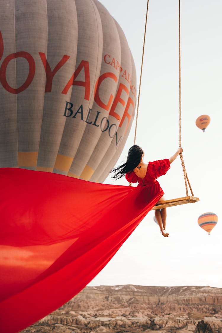 Woman In A Red Dress On A Swing And Hot Air Balloons