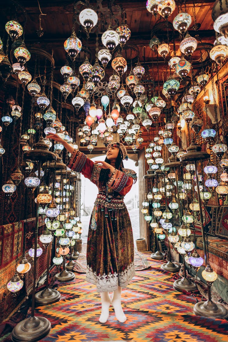 Woman In Traditional Costume In Shop With Lamps