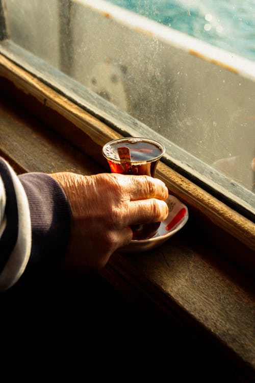 Photo of a Person's Hand Holding a Glass of Tea