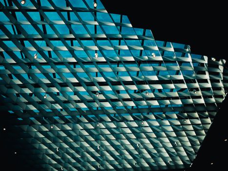 A striking architectural glass ceiling showcasing geometric patterns and a soft blue hue.