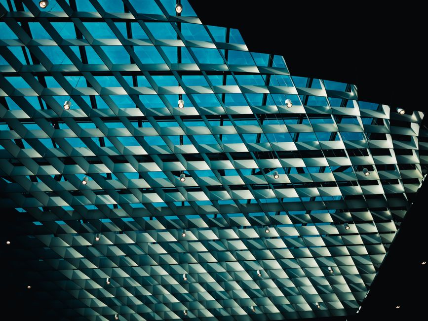 A striking architectural glass ceiling showcasing geometric patterns and a soft blue hue.