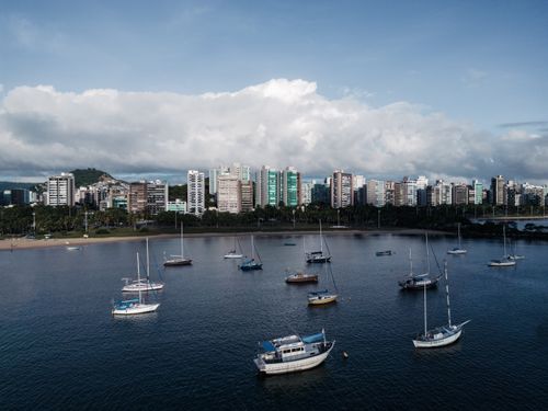Free A stunning aerial view of Enseada do Suá in Brazil, featuring boats and city skyline under a cloudy sky. Stock Photo