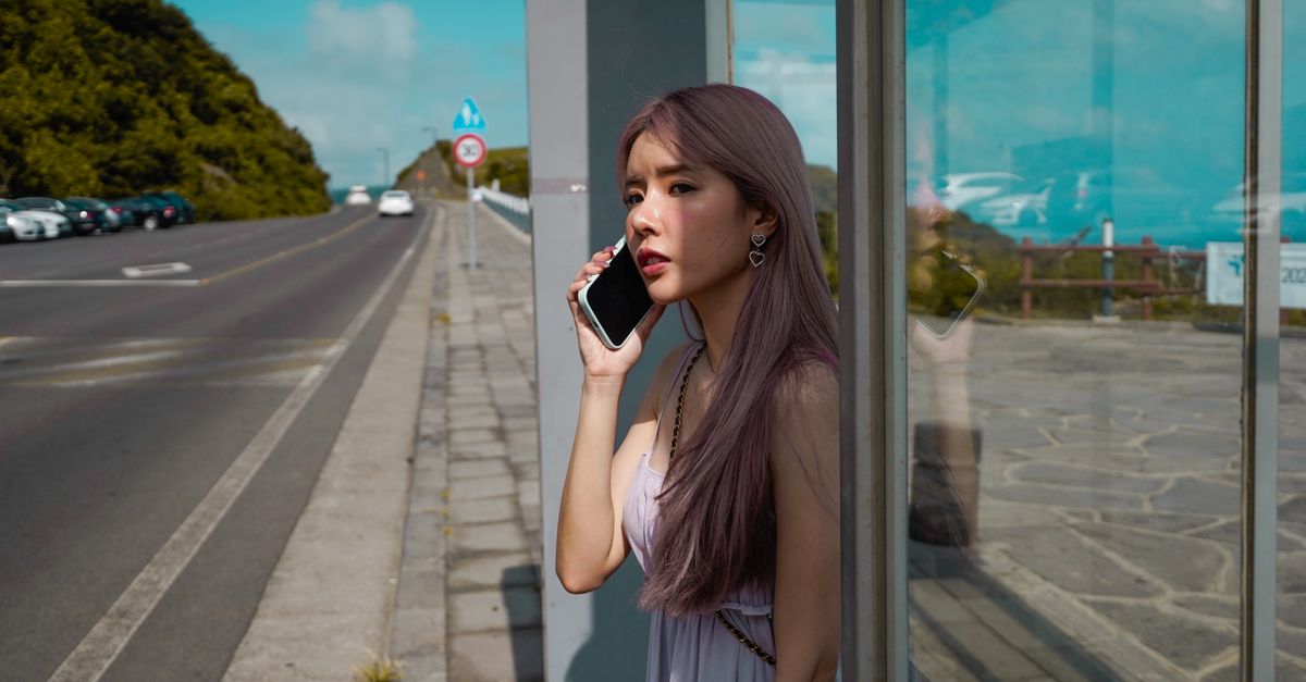 Hispanic woman on smartphone reviewing insurance options at a Florida bus stop