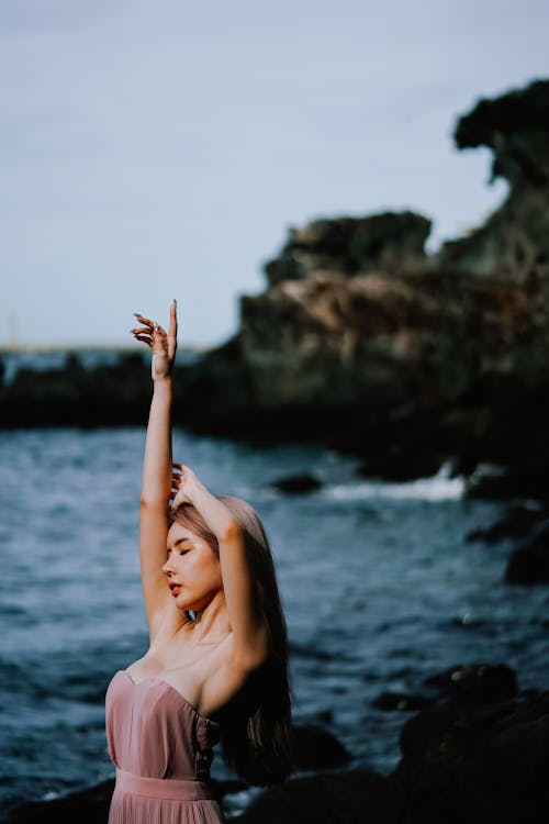 Woman Posing with Arm Raised on Shore