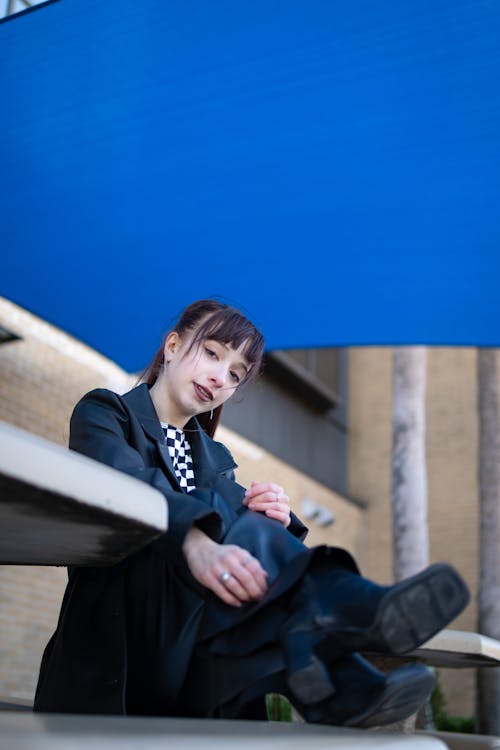 Young Woman in a Black Coat Sitting Outside 