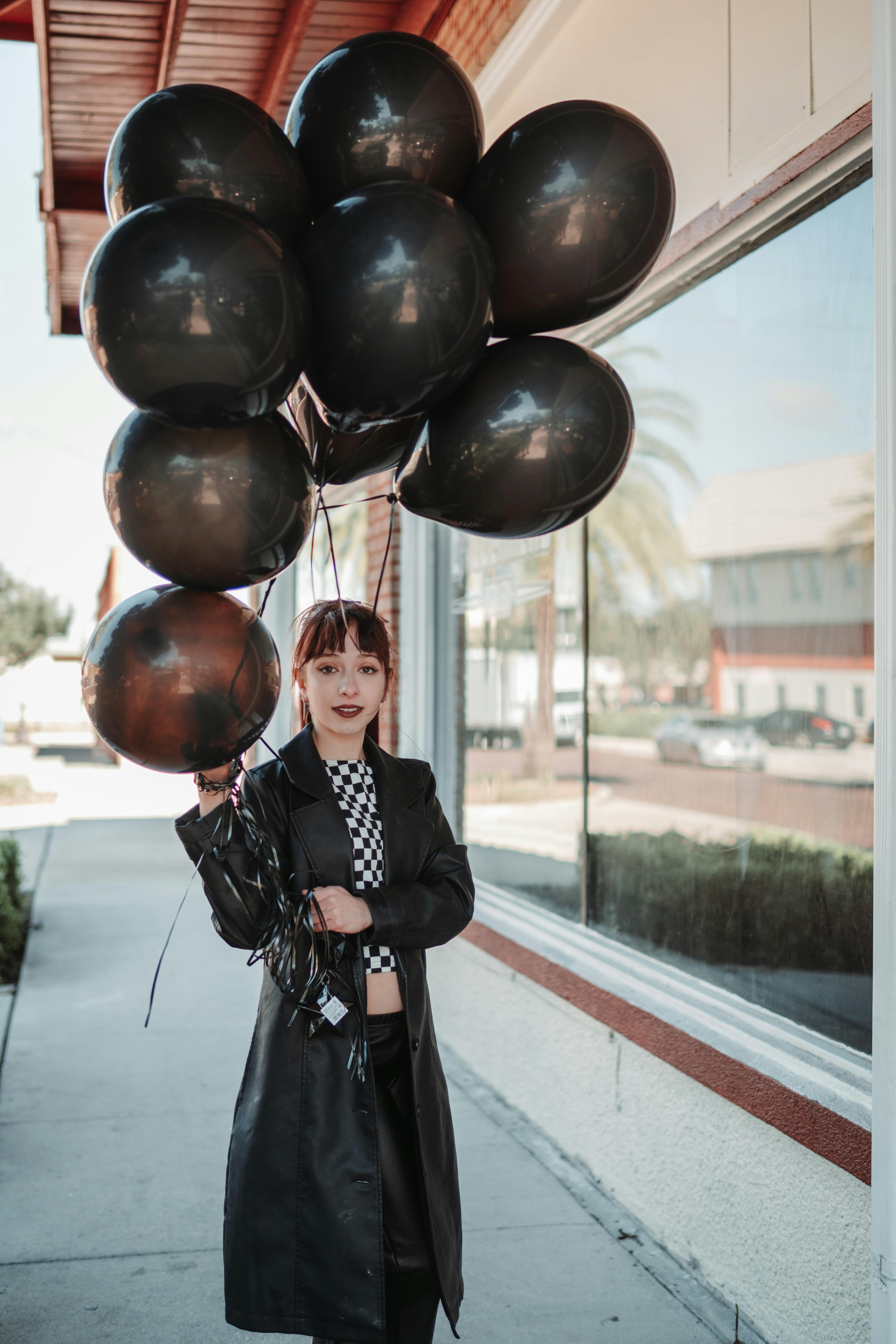 woman holding black baloons