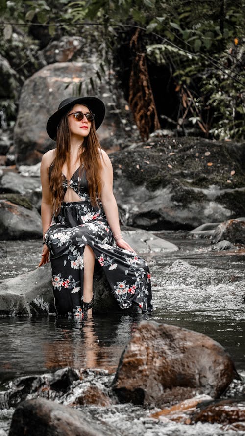 A Woman in Black Floral Dress Sitting on the River