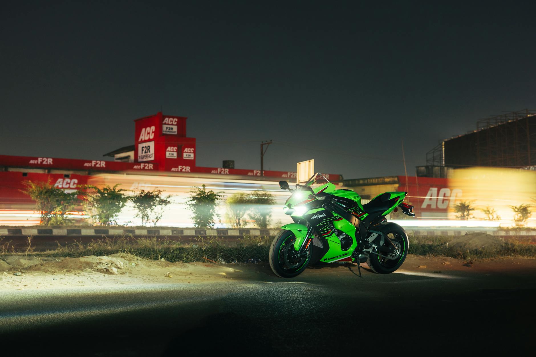 A green motorcycle is driving down a road at night