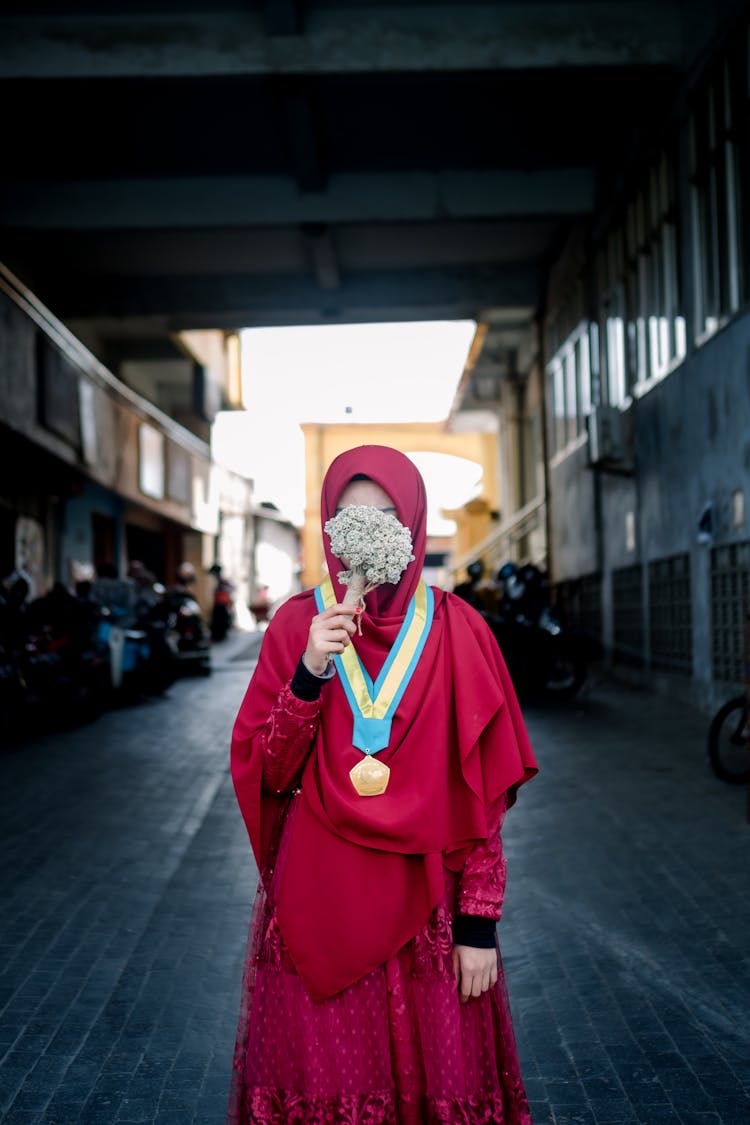 Woman With Medal Posing And Covering Face With Flowers