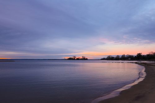 Free A tranquil beachfront scene at sunset with a vivid, dramatic sky over calm waters. Stock Photo