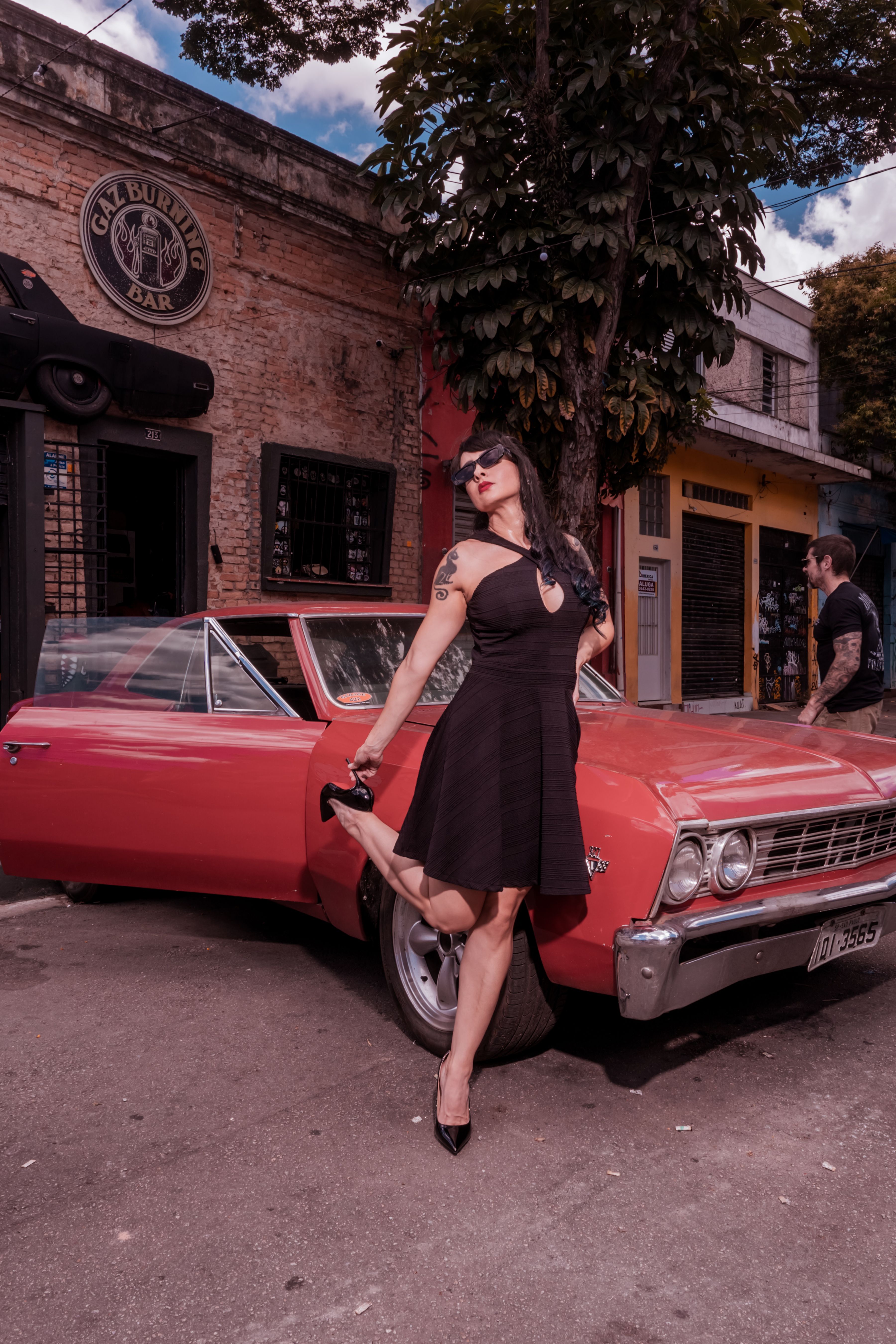 Woman in Black Dress Standing Beside a Red Vintage Car · Free Stock Photo