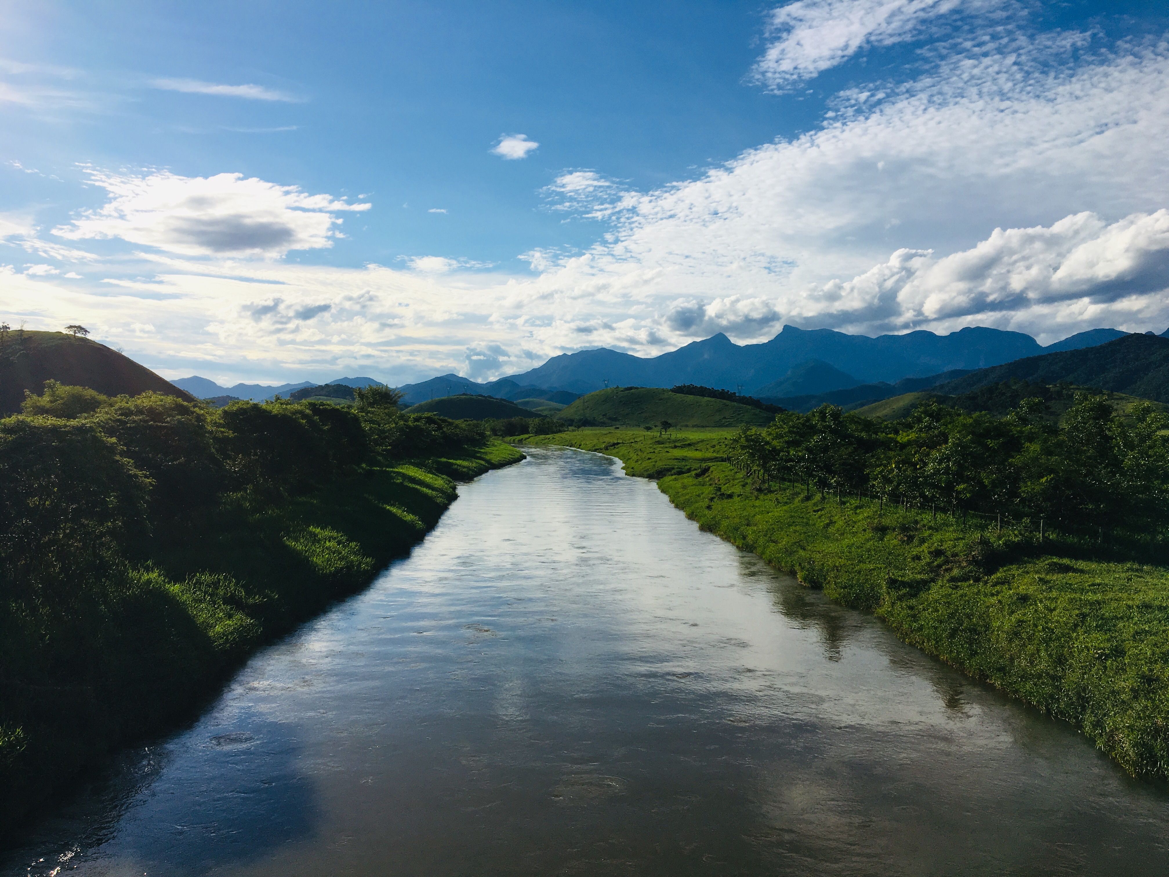 A picturesque river meandering through lush green landscapes under a blue sky with scattered clouds.