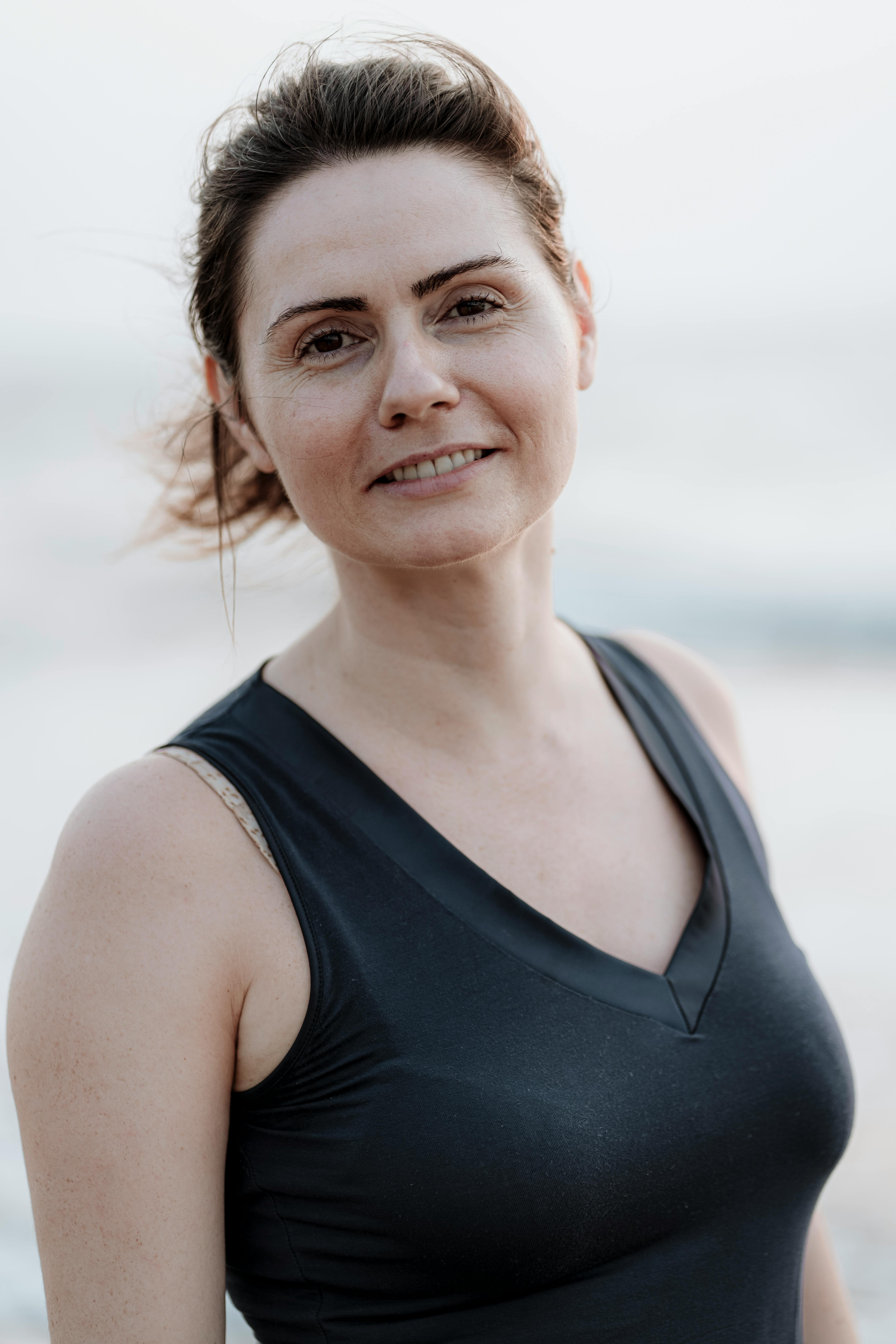 Natural portrait of a smiling woman in a tank top outside during summer.