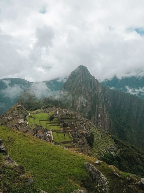 Free Stunning aerial shot of Machu Picchu surrounded by lush mountains and misty clouds, capturing Peru's iconic landmark. Stock Photo