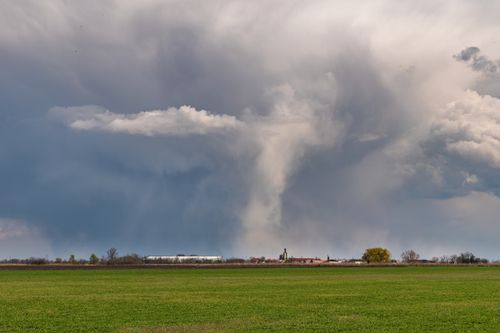 Free Expansive view of dramatic clouds over a green farmland field, showcasing nature's power. Stock Photo