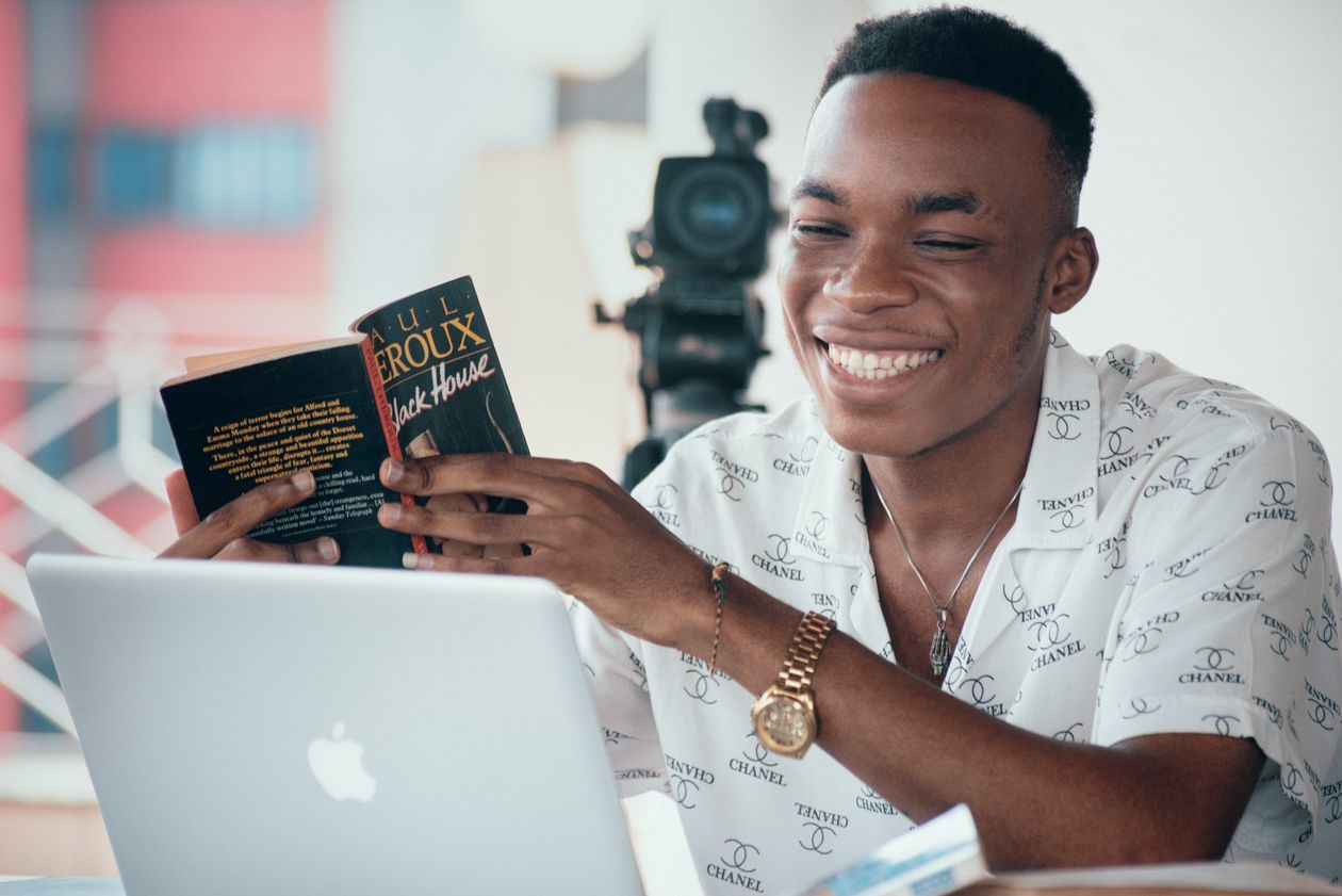 An African professional smiling while learning on a laptop with a notebook